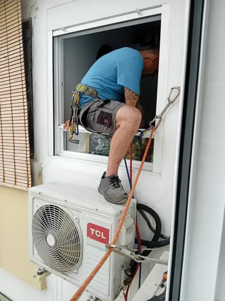 Técnico con arnés instalando TCL Inverter — Instalaciones Tomás
